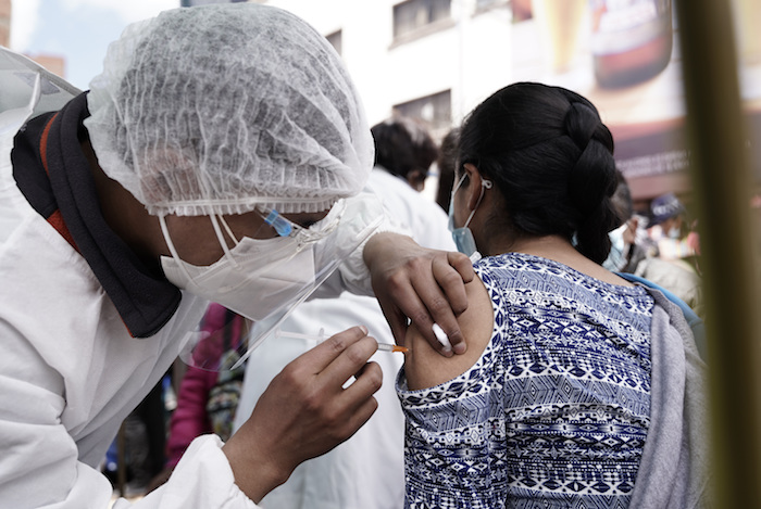 Un trabajador de salud aplica a una mujer la primera dosis de la vacuna Sinopharm fuera de la iglesia Monte de Oración en La Paz, Bolivia, el martes 28 de diciembre.