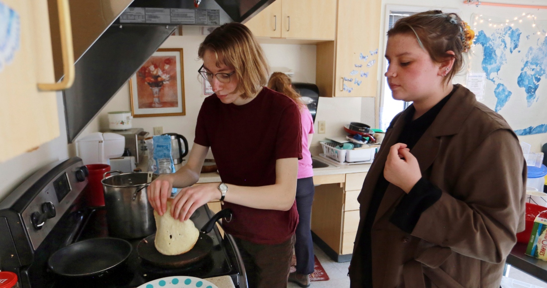 Las estudiantes Sophia Pavlenko, a la izquierda, de Rusia, y Masha Novikova, de Ucrania, preparan blinis, crepas al estilo de Europa del Este, para vender a sus compañeros en el United World College y recaudar fondos para apoyar a los ucranianos afectados por la guerra, en Montezuma, Nuevo México, el domingo 12 de marzo de 2022.
