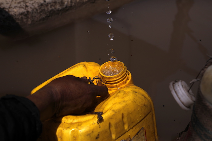 Una mujer recolecta agua en un recipiente, en una fotografía de archivo.
