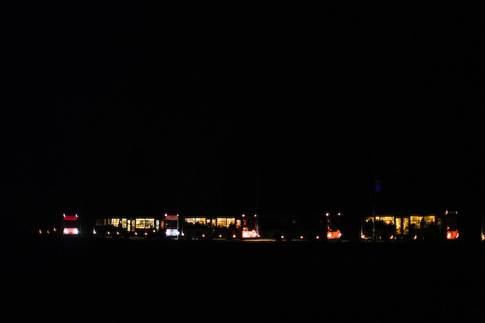 Autobuses que trasladan a civiles que huyeron de Mariúpol, algunos de ellos de la acería Azovstal, llegan durante un toque de queda a un centro de recepción de desplazados en Zaporiyia, Ucrania, la noche del domingo 8 de mayo de 2022.