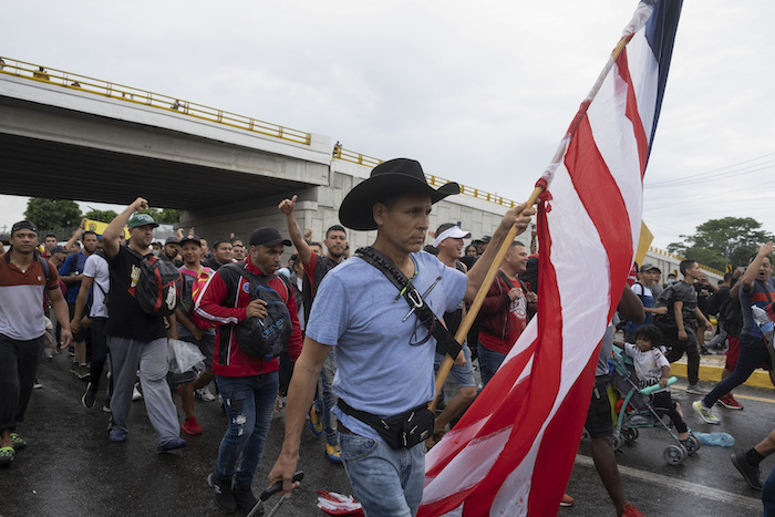 Un migrante lleva una bandera estadounidense mientras arrastra equipaje durante una caravana de migrantes que sale de la ciudad de Tapachula, en el estado de Chiapas, México, la madrugada del lunes 6 de junio de 2022.