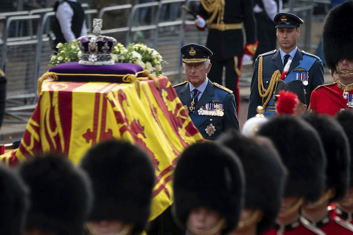 El rey Carlos III y el príncipe Guillermo siguen el ataúd de la reina Isabel II cubierto con la bandera real, portado en un carro con caballos en la procesión ceremonial desde el Palacio de Buckingham a la Sala Westminster del Parlamento, Londres, 14 de septiembre de 2022.