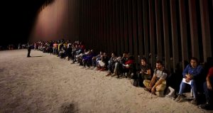 Migrantes esperan junto a un muro fronterizo el 23 de agosto del 2022, tras cruzar desde México cerca de Yuma, Arizona.