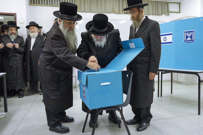Judíos ultraortodoxos miran los votos de su rabino Israel Hager durante las elecciones de Israel en Bnei Brak, el martes 1 de noviembre de 2022.