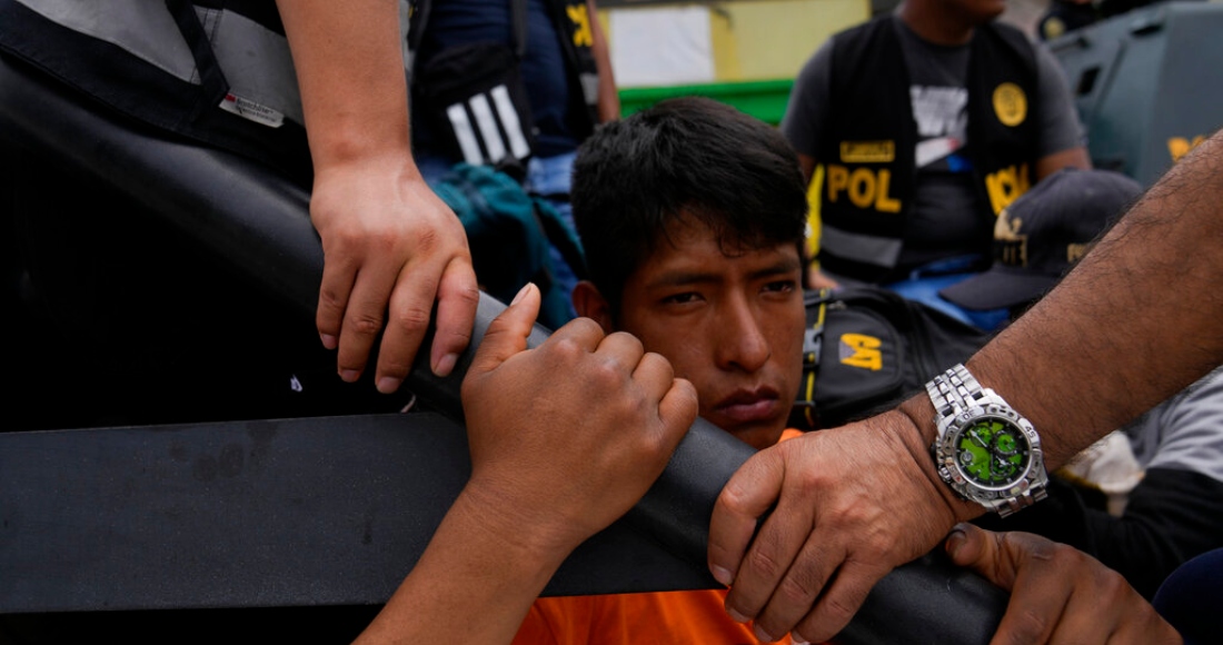 Un manifestante antigubernamental detenido se sienta en la parte trasera de una camioneta de la policía en la Universidad de San Marcos en Lima, Perú, el sábado 21 de enero de 2023.
