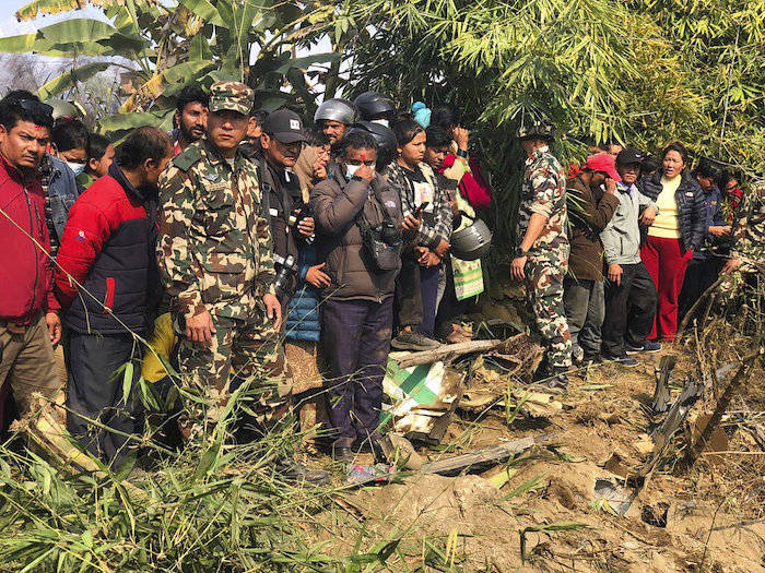 Varias personas observan los restos de un avión de pasajeros accidentado el domingo 15 de enero de 2023, en Pokhara, Nepal.