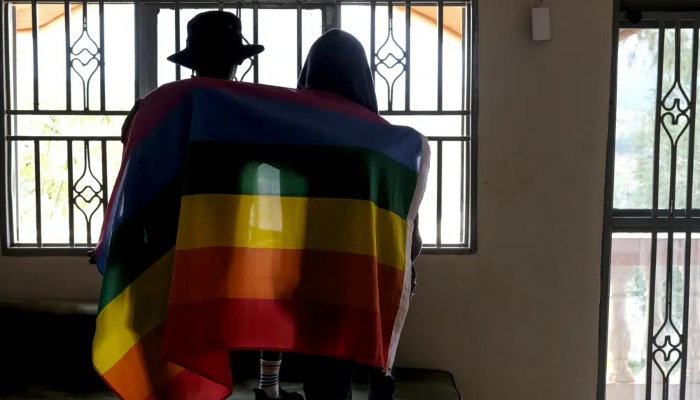 Una pareja gay de Uganda se cubre con una bandera del orgullo LGBT+ mientras posan para una fotografía, el 25 de marzo de 2023. El Presidente, Yoweri Museveni, promulgó una nueva y dura legislación contra las personas homosexuales apoyada por muchos en el país, pero ampliamente condenada por activistas de derechos humanos y otras personas en el extranjero, se anunció el lunes 29 de mayo de 2023. Foto: AP, Archivo