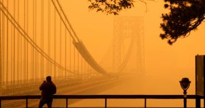 Un hombre conversa por su teléfono en medio de una bruma de humo cerca del puente George Washington, en esta imagen tomada desde Fort lee, Nueva Jersey, el miércoles 7 de junio de 2023. FOTO: Seth Wenig, AP