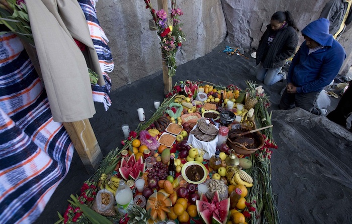 Pobladores locales hacen una plegaria con una ofrenda de comida en una ceremonia en las laderas del volcán Popocatépetl en México, el 12 de marzo de 2014. Los habitantes de los pueblos que rodean al volcán suben por sus laderas para hacer ofrendas y tocar música pidiendo a la montaña que los libre de sus erupciones.