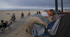 Varias personas en bicicleta pasan frente a un campamento de indigentes a lo largo del malecón del vecindario Venice de Los Ángeles. Foto: Jae C. Hong, AP. 