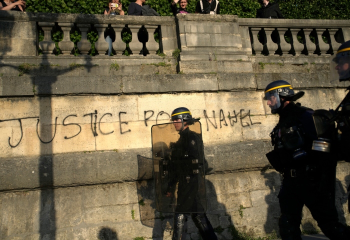 Policías patrullando junto a un graffiti que dice "Justicia para Nahel" mientras varios jóvenes se reúnen en la Plaza de la Concordia durante una protesta en París, Francia, el viernes 30 de junio de 2023. Foto: Lewis Joly, AP, Archivo