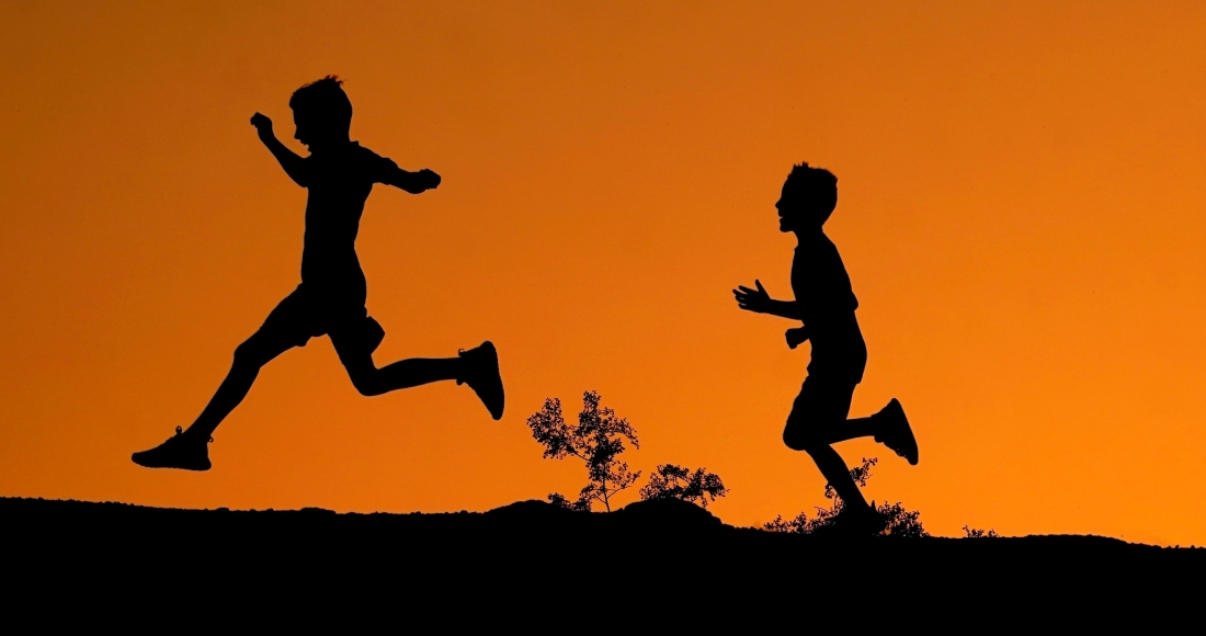 La silueta de dos niños se ve recortada contra el cielo al atardecer mientras corren por una colina en el Parque Papago, el 1 de abril de 2022 en Phoenix.
