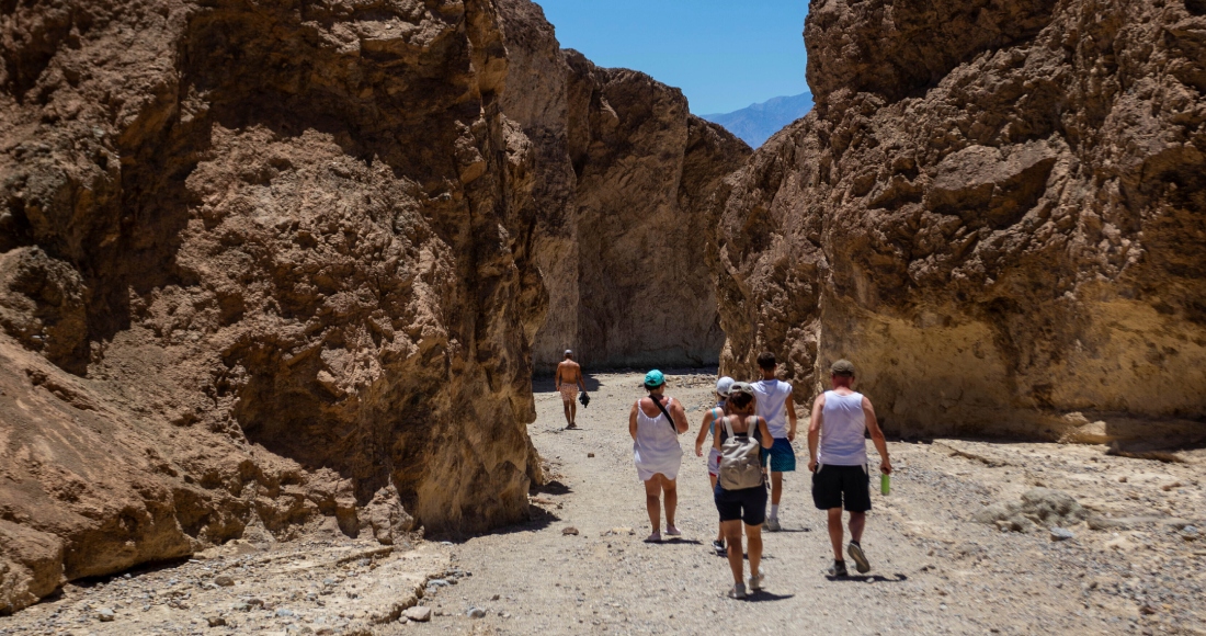 Varios excursionistas regresan a sus vehículos luego de recorrer parte del cañón Golden en el Parque Nacional Valle de la Muerte, California, el martes 11 de julio de 2023.