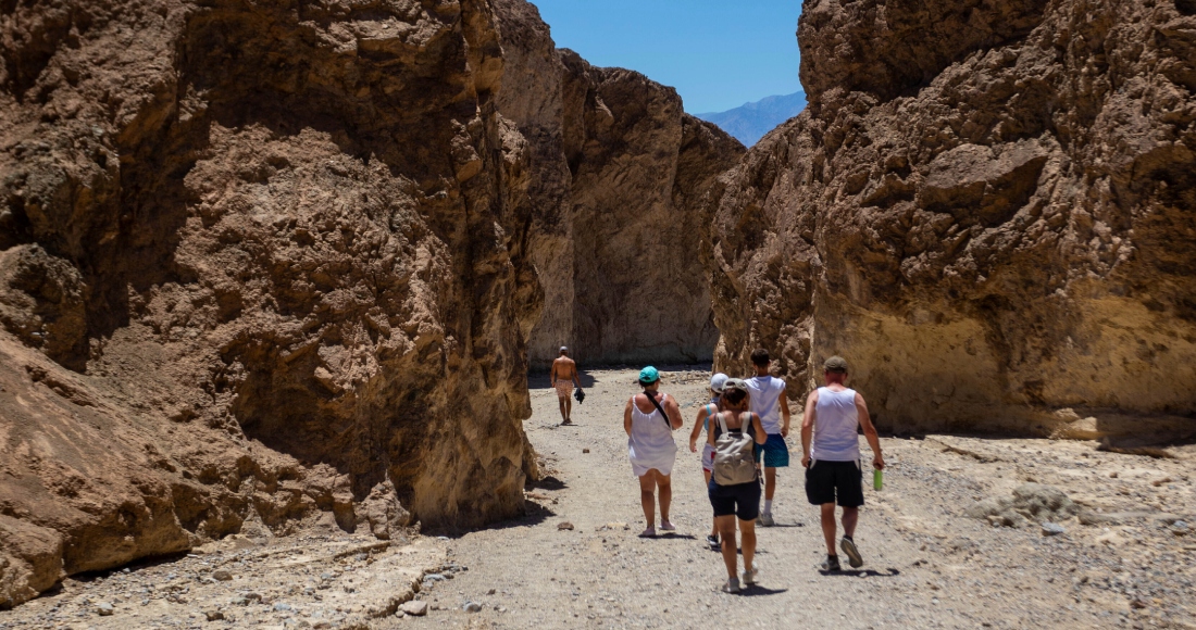 Varios excursionistas regresan a sus vehículos luego de recorrer parte del cañón Golden en el Parque Nacional Valle de la Muerte, California, el martes 11 de julio de 2023.