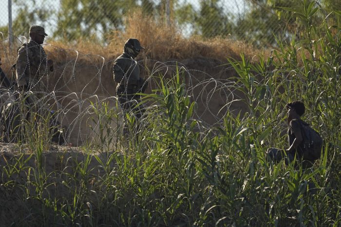 Elementos de las fuerzas de seguridad de Texas hablan con un migrante que cruzó el río Bravo (Grande) desde México, el martes 1 de agosto de 2023, en Eagle Pass, Texas.