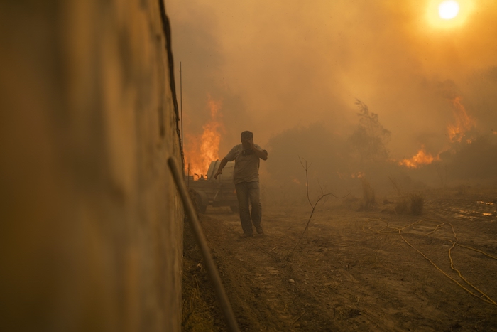 Un residente corre para evitar las llamas de un incendio localizado en Gennadi, en la isla de Rodas, en el sureste de Grecia, el 25 de julio de 2023.