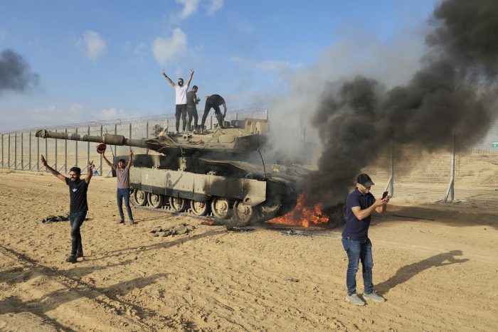 Palestinos festejan al lado de un tanque israelí destruido en una valla en la Franja de Gaza, al este de Khan Younis, el sábado 7 de octubre de 2023.