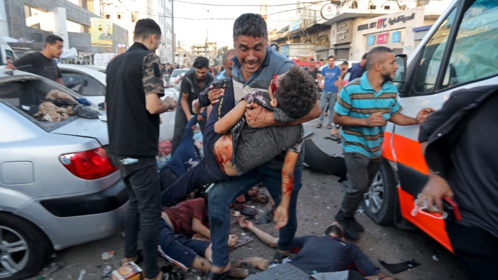 Un hombre que carga a un niño pasa encima de los cuerpos de palestinos muertos y heridos que yacen en el suelo tras un ataque aéreo israelí frente a la entrada del hospital Al Shifa, el viernes 3 de noviembre de 2023, en la Ciudad de Gaza.