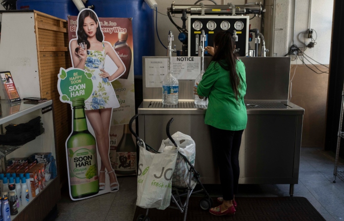 La madre de Deneffy Sánchez, Lilian López, rellena sus botellas de agua en una tienda de comestibles.