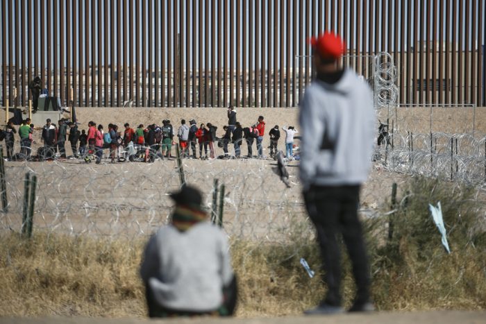 Migrantes hacen fila junto al muro fronterizo con Estados Unidos después de ser detenidos por las autoridades migratorias estadounidenses, vistos desde el lado de Ciudad Juárez, México, el 27 de diciembre de 2023.