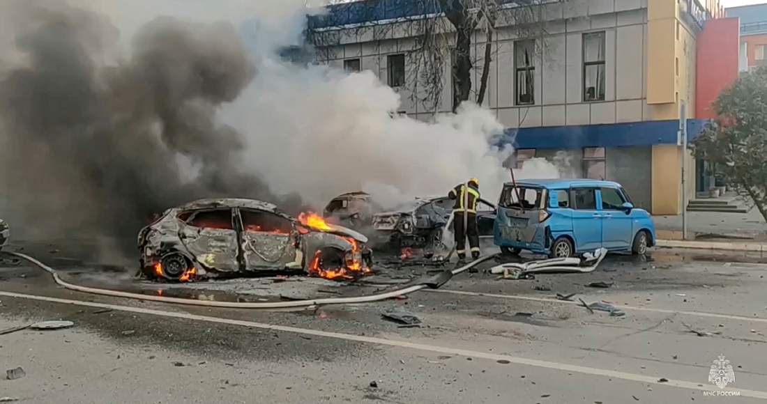 En esta fotografía tomada de un video difundido por el canal de Telegram del Ministerio de Situaciones de Emergencia de Rusia el sábado 30 de diciembre de 2023, se ve a bomberos que extinguen vehículos en llamas después de un ataque en Belgorod, Rusia.