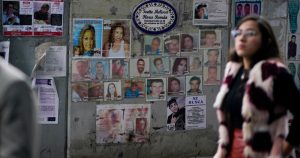 Una mujer pasa frente a fotografías de personas desaparecidas frente a la Procuraduría General de Justicia, en Ciudad de México. Foto: Eduardo Verdugo, AP.