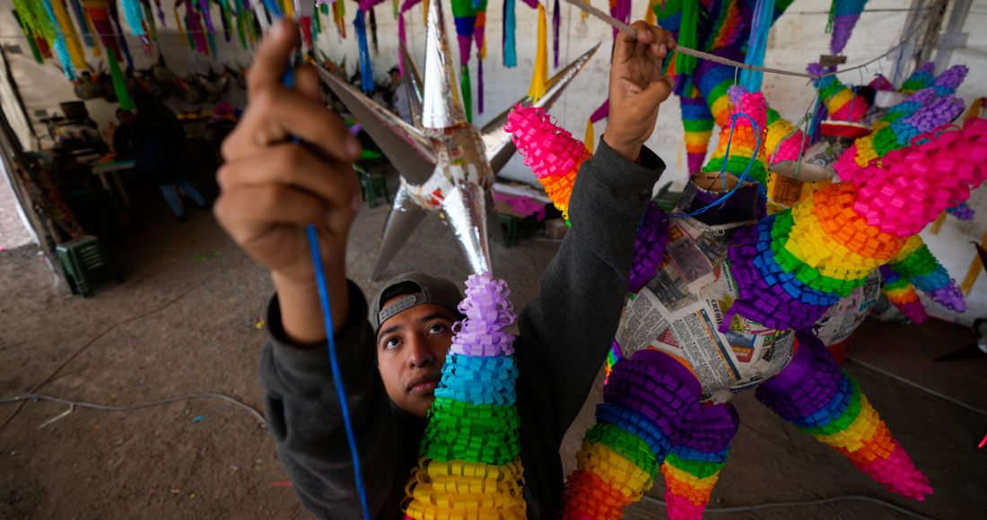 Un trabajador cuelga una piñata con la tradicional forma de esfera con siete picos, que se rellena con frutas y dulces, en un negocio familiar en Acolman, al norte de Ciudad de México, el miércoles 13 de diciembre de 2023. Esta artesanía tradicional tiene un origen religioso y está cargada de simbolismo: cada cono representa uno de los siete pecados capitales, por eso se golpea la piñata hasta destruirla como una forma de alejarse de esos pecados.