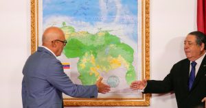 El presidente de la Asamblea Nacional, Jorge Rodríguez (izquierda), y el presidente de la Comisión Especial para la Defensa de Guyana Esequibo, Hermann Escarra, se dan la mano después de revelar el nuevo mapa de Venezuela que incluye el territorio del Esequibo, una franja de tierra administrada y controlada por Guyana pero reclamada por Venezuela, en Caracas, Venezuela, el viernes 8 de diciembre de 2023. (Foto AP/Matías Delacroix)