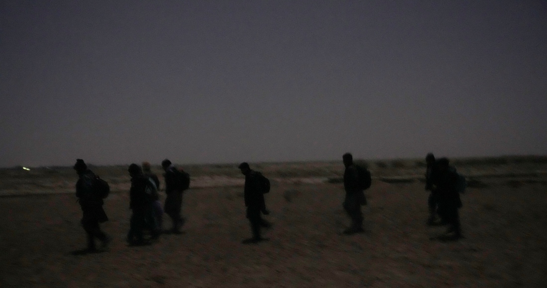 Jóvenes migrantes chiíes afganos caminan hacia el muro fronterizo entre Irán y Afganistán en el desierto en las inmediaciones de la ciudad de Zaranj, Afganistán, tratar de saltarlo, el 25 de diciembre de 2023. Imagen ilustrativa.