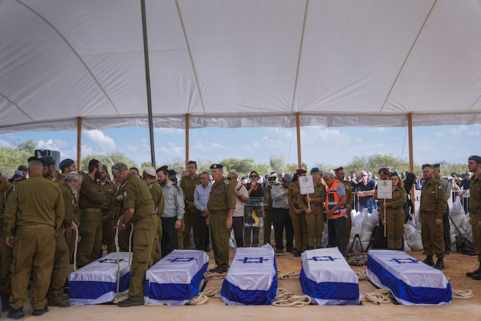 Un grupo de dolientes se congregan alrededor de los féretros de cinco miembros de la familia Kotz durante su funeral en Gan Yavne, Israel, el 17 de octubre de 2023.