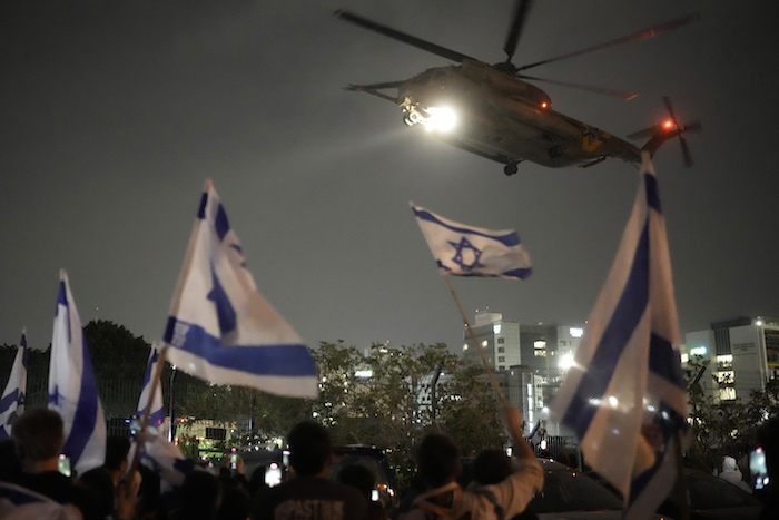 Varias personas ondean banderas israelíes bajo un helicóptero que traslada a rehenes liberados por Hamás en Gaza a su llegada al helipuerto del hospital infantil Schneider, en Petah Tikva, Israel, el 26 de noviembre de 2023.