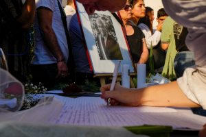 Un retrato del fallecido expresidente chileno Sebastián Piñera en el punto de homenaje colocado en la sede del partido Renovación Nacional, mientras una mujer firma en el libro de condolencias, en Santiago, Chile, el martes 6 de febrero de 2024.