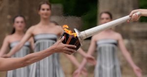 La actriz Mary Mina, que interpreta a una sacerdotisa, a la derecha, enciende una antorcha durante la ceremonia oficial para los Juegos Olímpicos de París, en la Antigua Olimpia, Grecia, el martes 16 de abril de 2024. Foto: Thanassis Stavrakis, AP.