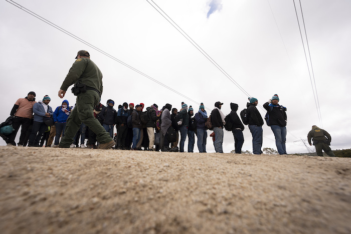 Hombres que solicitan asilo, incluidos peruanos, hacen fila mientras esperan a ser procesados tras cruzar la frontera cercana con México, el jueves 25 de abril de 2024 en Boulevard, California.