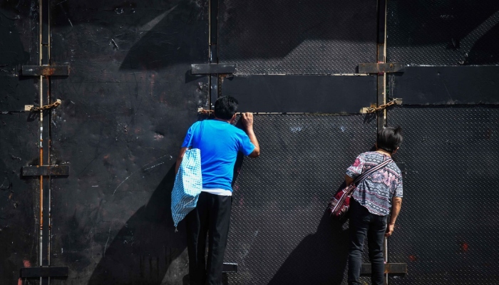 Personas observan Palacio Nacional a través de las vallas que lo resguardan.