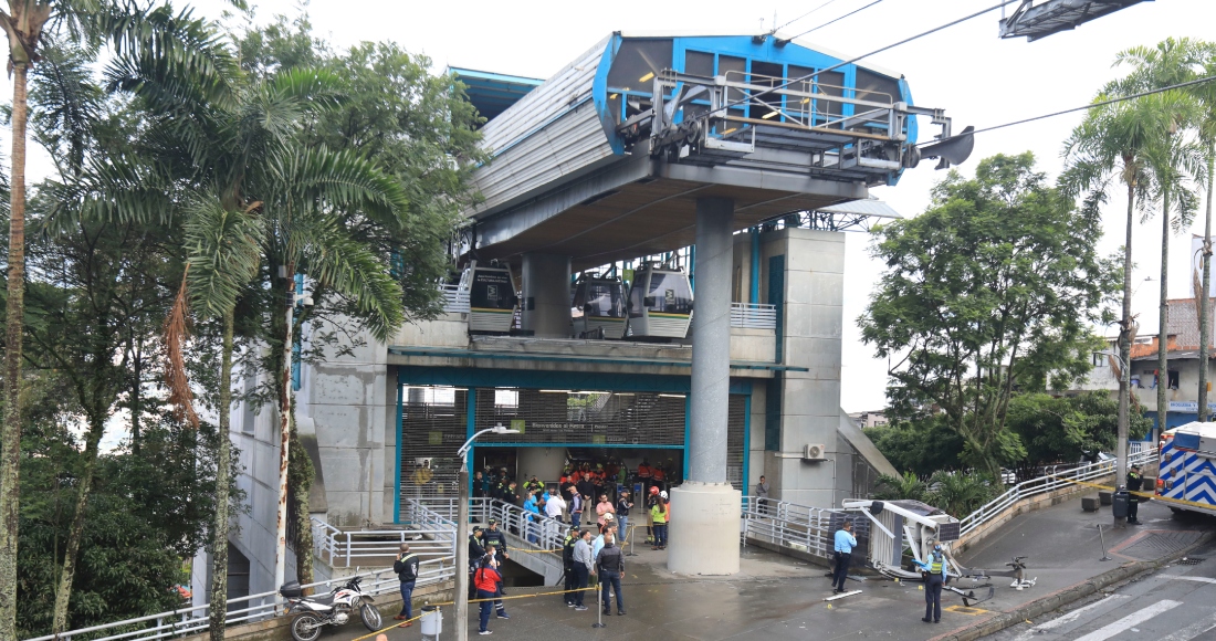 Un teleférico yace en el suelo, a la derecha, después de caer en Medellín, Colombia, el miércoles 26 de junio de 2024. Al menos una persona murió y otras 12 resultaron heridas cuando el teleférico se desplomó mientras se acercaba a una estación, dijeron las autoridades locales. 