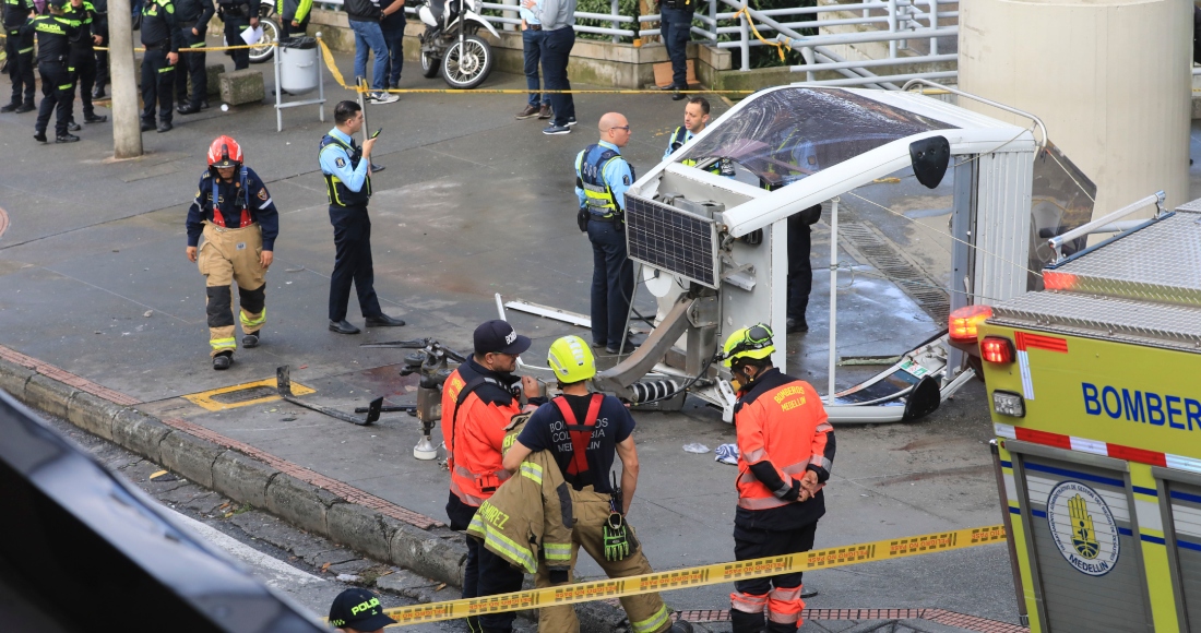 La policía y los bomberos esperan junto a un teleférico tirado en el suelo después de caer en Medellín, Colombia, el miércoles 26 de junio de 2024. Al menos una persona murió y otras 12 resultaron heridas cuando el teleférico se derrumbó mientras se acercaba a una estación, dijeron autoridades locales.