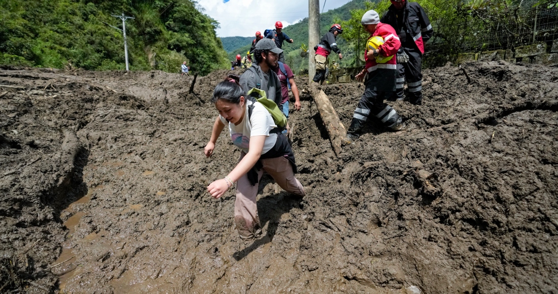 Residentes y trabajadores de rescate avanzan por vía llena de lodo tras las intensas lluvias que provocaron un deslizamiento de tierra en Baños de Agua Santa, Ecuador, el lunes 17 de junio de 2024.