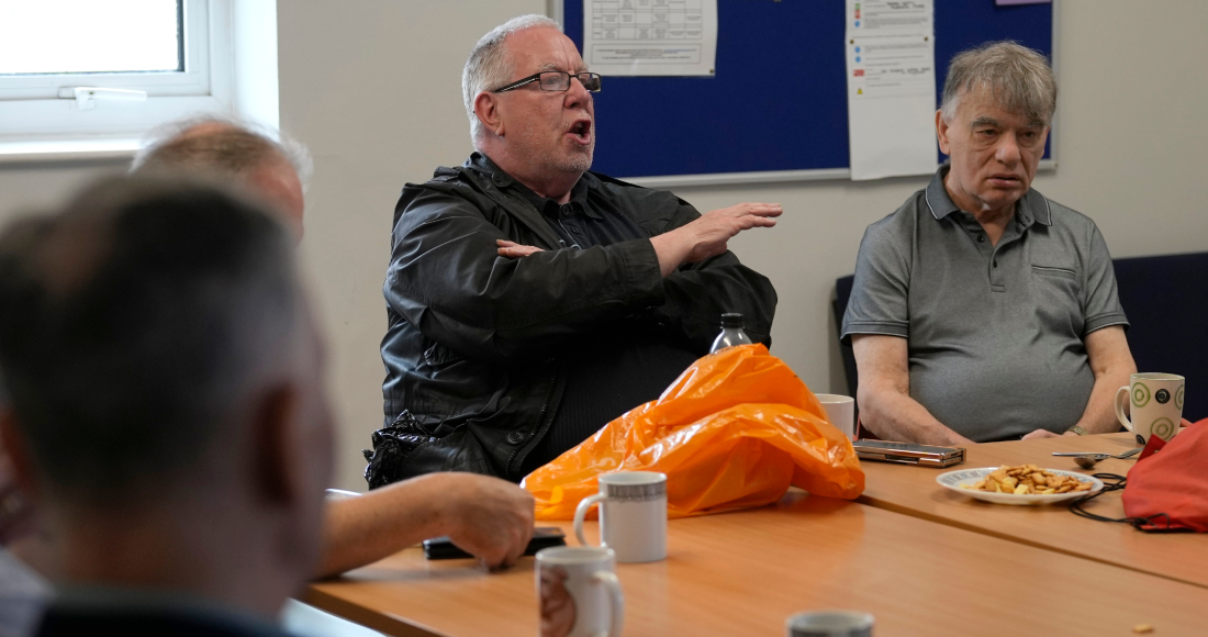 Barrie Stradling, a la izquierda, habla durante el almuerzo semanal de unos 20 jubilados en el centro comunitario Tredegar de Bow, el jueves 16 de mayo de 2024, en el este de Londres.