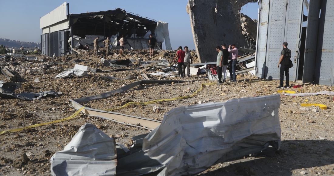 Un grupo de personas se congregan junto a un hangar alcanzado por un ataque aéreo israelí, en Jiyeh, Líbano, el 25 de septiembre de 2024. 