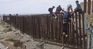 Migrantes saltan el muro fronterizo entre México y EU en Tijuana.