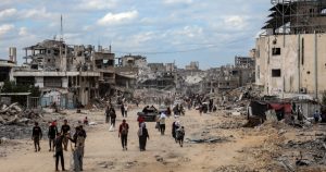 Palestinos caminan entre los escombros de los edificios destruidos tras regresar a Khan Younis, en el sur de la Franja de Gaza, el 12 de octubre de 2025.