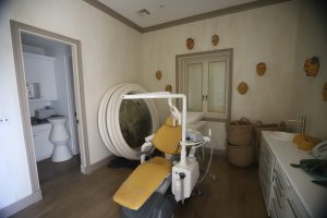 Un cuarto, adornado con máscaras de hombres adultos, muestra una silla de dentista.